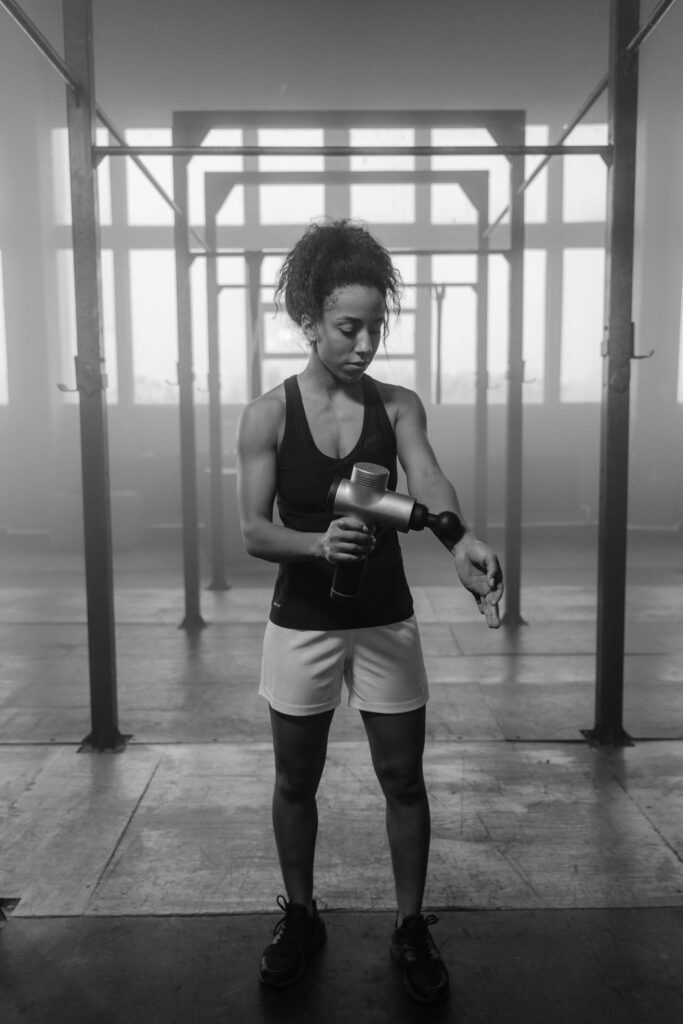 Woman using a massage gun to relax after a workout.