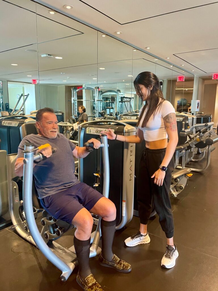 Personal trainer sharing a fun gym moment with a legendary bodybuilding figure.