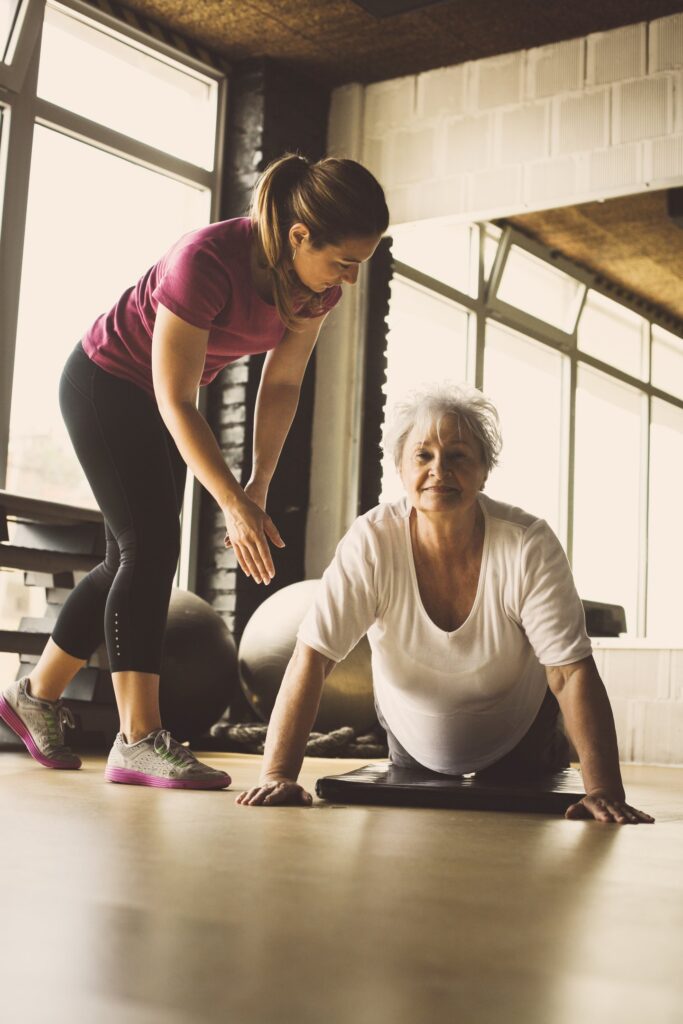 In-home personal trainer helping a client perform a controlled spine extension mobility drill.